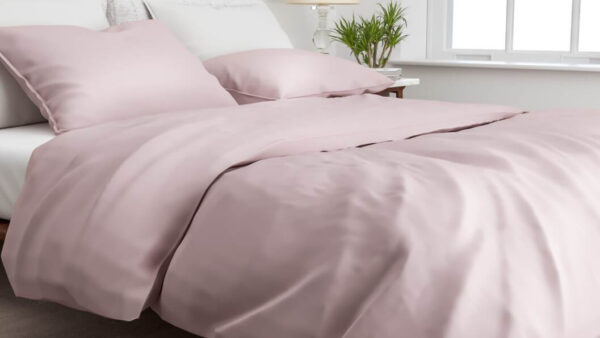 bed opgedekt met katoen-satijn dekbedovertrek in de kleur licht roze shady pink